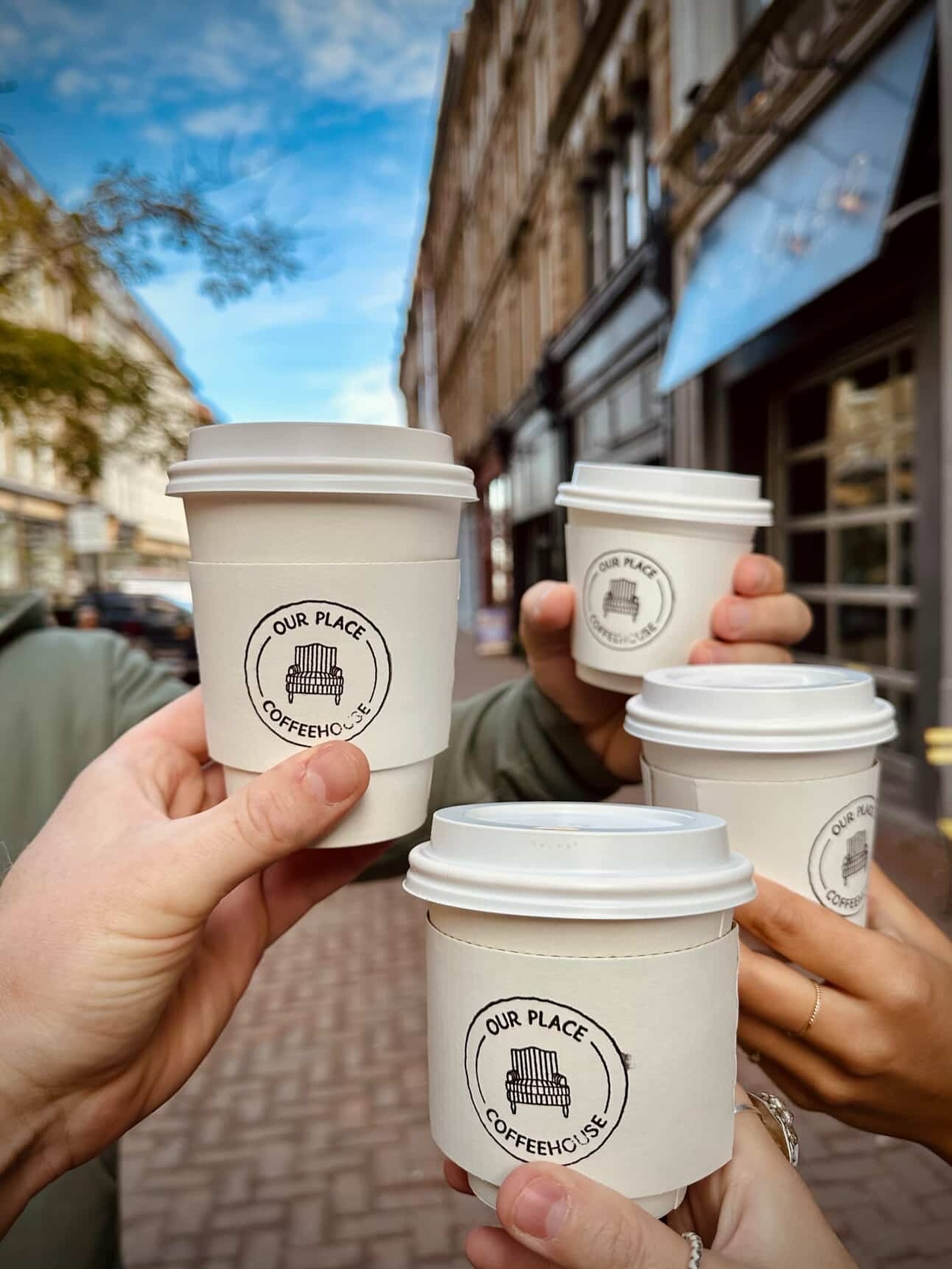 Friends raising four Our Place takeaway coffee cups outside