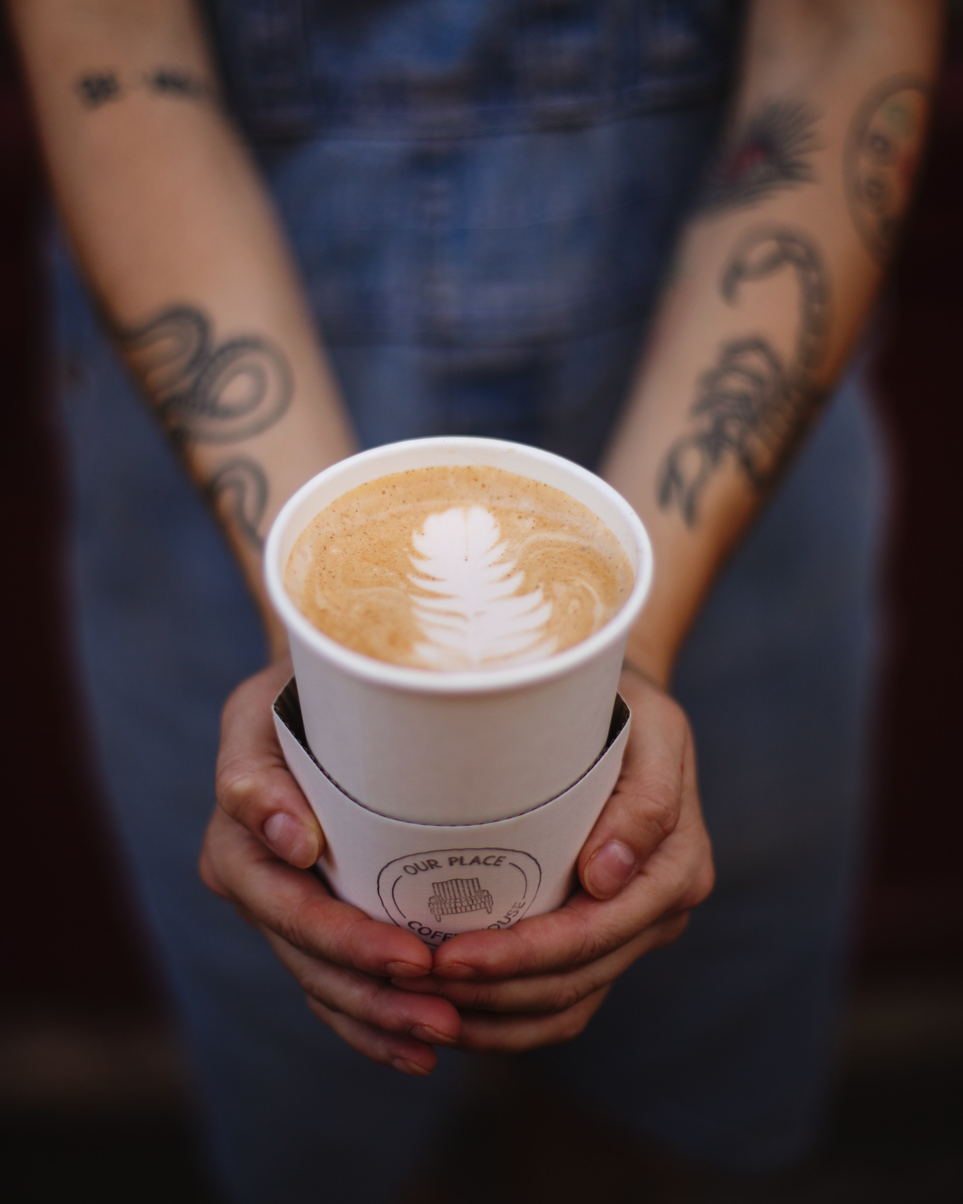 A barista presenting a latte with leaf art