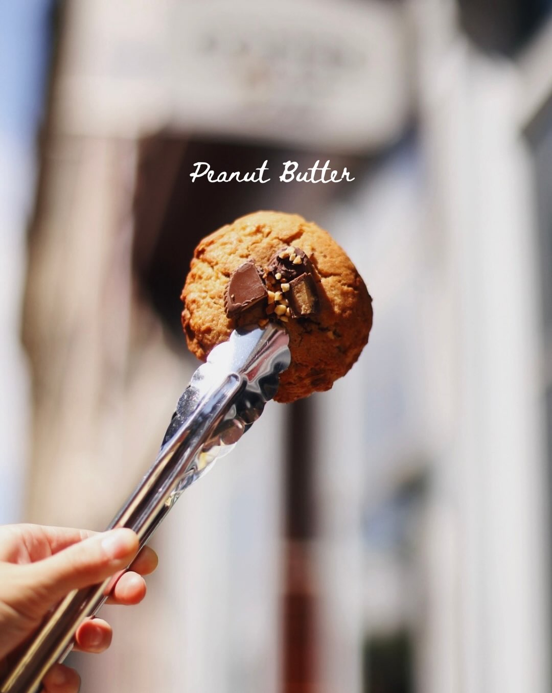 A house-made peanut butter cookie held in pastry tongs